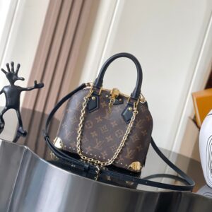 Alma BB handbag. The bag is crafted from Monogramst canvas with deep leather trim, accented with striking metal corner protectors and studs. This version features a detachable chain that can be worn with the adjustable shoulder strap. Can be used alone or with other accessories.  19x11x22 cm